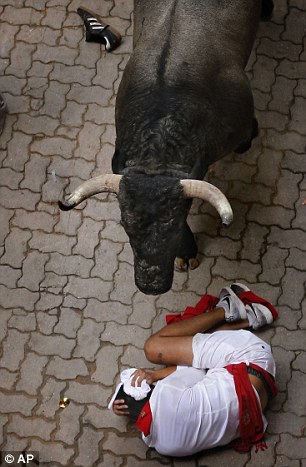36186FA900000578-0-A_male_runner_cowers_beneath_a_bull_during_the_infamous_Pamplona-a-139_1468102425899.jpg